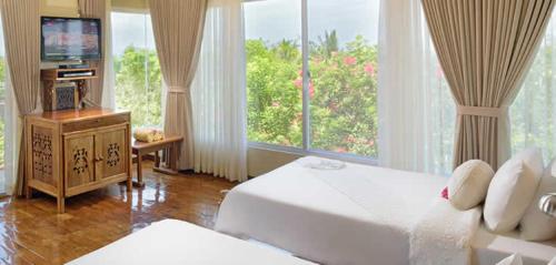 a hotel room with a bed and a large window at Amarela Resort in Panglao Island