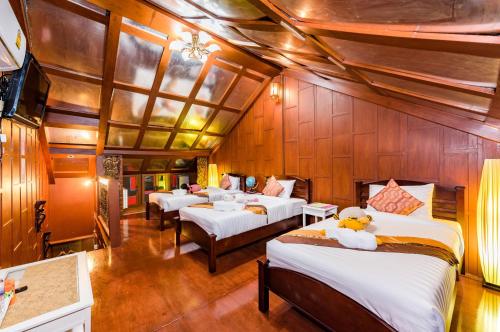 a bedroom with four beds in a room with wooden walls at Baan Ratchapruek in Phuket Town