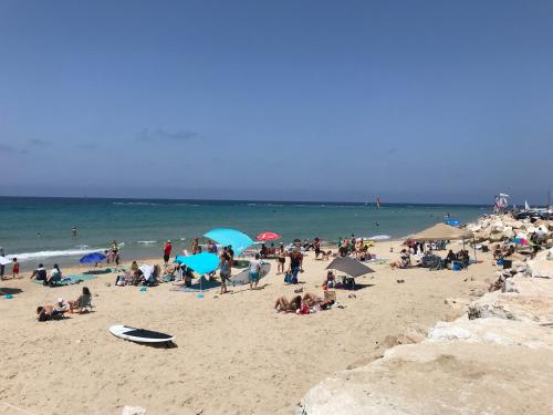 a crowd of people on a beach with umbrellas at Different Atmosphere Suite in Caesarea