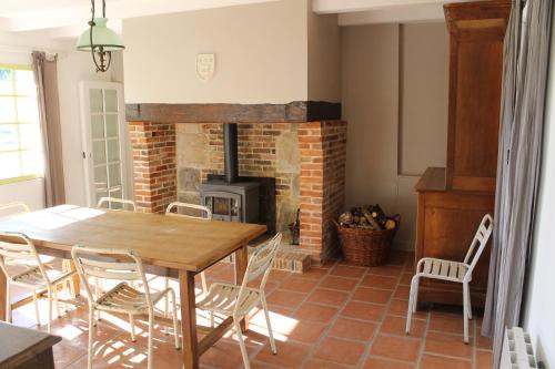 une salle à manger avec une table et une cheminée en briques dans l'établissement Propriété à 5 km de Honfleur, à Fourneville