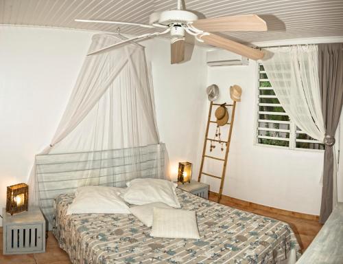 a bedroom with a bed with a ceiling fan at Villa les Alizés in Les Trois-Îlets