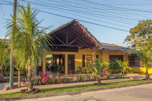 a yellow building with palm trees in front of it at Hotel Amazon Bed And Breakfast in Leticia