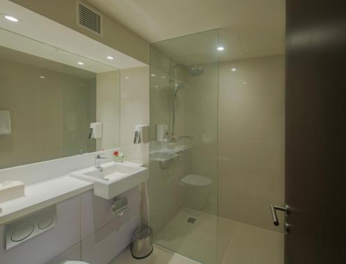 a white bathroom with a sink and a shower at Bigland Hotel & Convention Sentul in Bogor