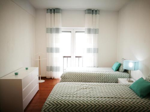 a bedroom with two beds and a window at Peniche's Blue & White in Peniche