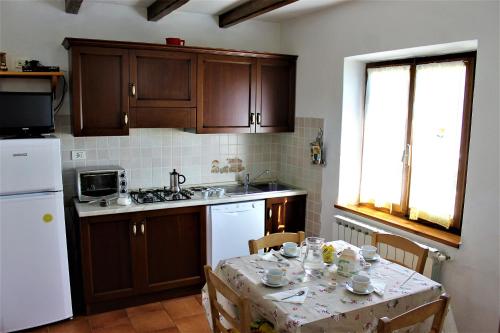 a kitchen with a table and a white refrigerator at Cottage Abetone La Capanna in Tuscany in Abetone