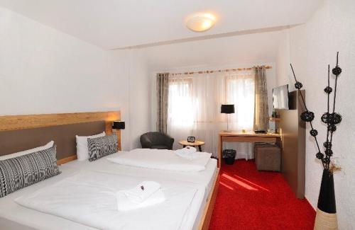 a bedroom with a large white bed and a red carpet at Vico's Hotel & Restaurant Asperg in Asperg