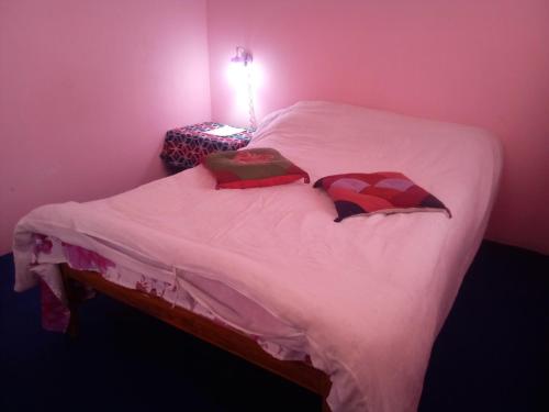 a bedroom with a white bed with two pillows at Everest Home Stay Apartment in Pātan