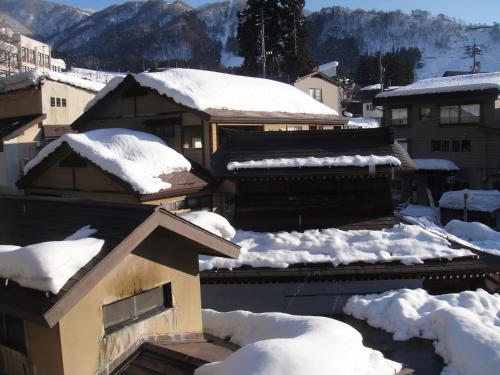 a snow covered roof of a building with snow on it at Ryokan Sakaya in Nozawa Onsen