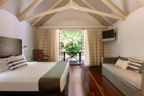 um quarto com uma cama grande e um sofá em Palm Bungalows em Hamilton Island