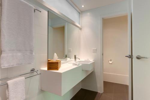 een witte badkamer met een wastafel en een spiegel bij Palm Bungalows in Hamilton Island