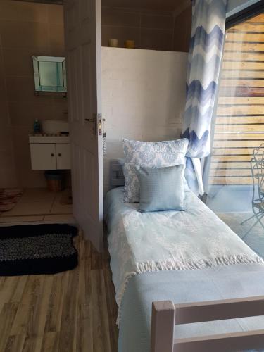 a bedroom with a bed with blue pillows and a window at Clanwilliam Hills House in Clanwilliam