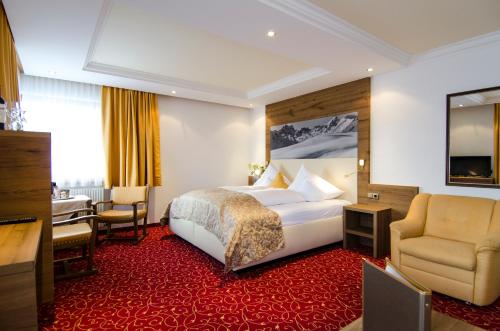 イシュグルにあるHotel Garni Pra Postaのベッド、デスク、椅子が備わるホテルルームです。