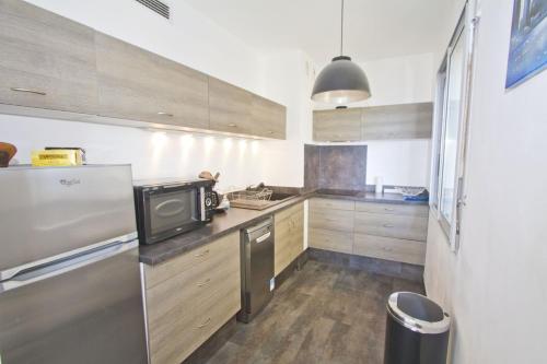 une cuisine avec des armoires en bois et un réfrigérateur en acier inoxydable dans l'établissement MILORD PROMENADE 2 - PROMENADE HOLIDAY, à Nice