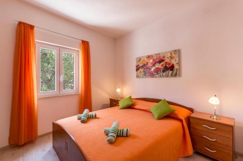 Schlafzimmer mit einem Bett mit orangefarbener Bettwäsche und grünen Kissen in der Unterkunft Apartments Petra in Bol