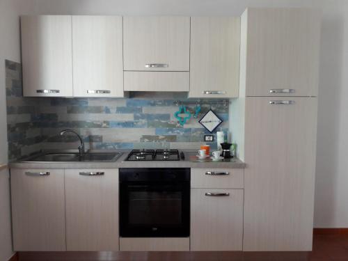 a kitchen with white cabinets and a sink and a stove at Casammare in Marina di Modica