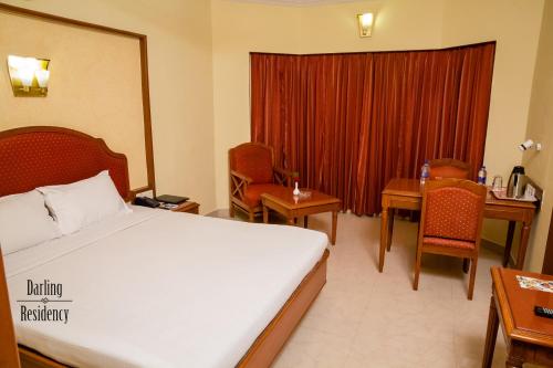 a hotel room with a bed and a table and chairs at Darling Residency in Vellore