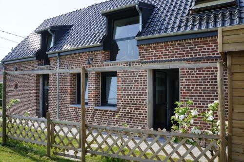 a brick house with a wooden fence at Gîte l'Atelier in Lecelles