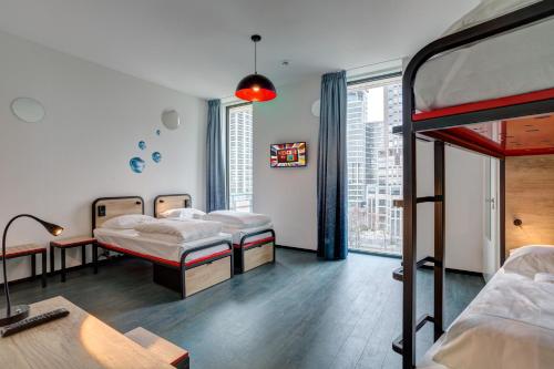 een kamer met 3 bedden en een raam bij MEININGER Hotel Amsterdam Amstel in Amsterdam