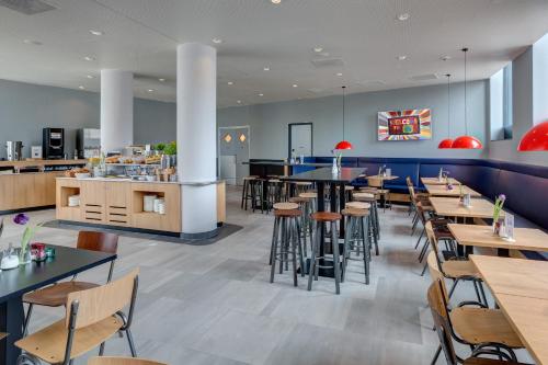 a restaurant with tables and chairs and a bar at MEININGER Hotel Amsterdam Amstel in Amsterdam