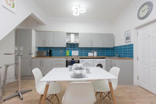 a white kitchen with a white table and chairs at Townhouse PLUS @ West Street Crewe in Crewe