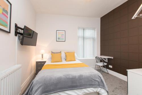 a bedroom with a bed with yellow pillows and a desk at Townhouse PLUS @ West Street Crewe in Crewe