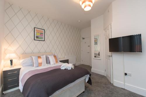 a bedroom with a bed and a flat screen tv at Townhouse PLUS @ West Street Crewe in Crewe
