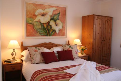 a bedroom with a bed with a painting on the wall at Mandeley Guest House in Helston