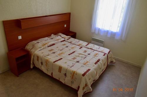 サン・ポール・レ・ダックスにあるRésidence Hotelière Les Acanthesのベッドルーム1室(木製ヘッドボード付きのベッド1台付)