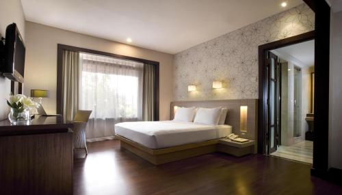 a bedroom with a bed and a window and a mirror at Hotel Santika Bandung in Bandung