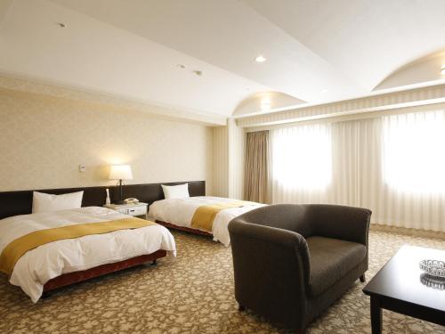 a hotel room with two beds and a chair at Kotohira Onsen Kotosankaku in Kotohira