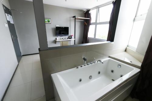 a bathroom with a tub and a television in it at Hotel 99 Botanik Klang in Klang