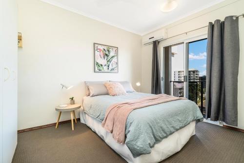 a white bedroom with a bed and a window at Huge CBD Top Floor Apartment with Breath Taking Views! in Darwin