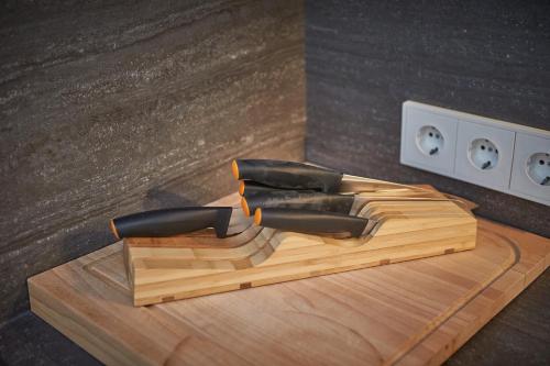 a wooden cutting board with four knives on it at Chalet Guter Hirte in Saalbach Hinterglemm