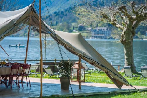 a tent with tables and chairs next to a lake at Hôtel Beau Site Talloires B SPA in Talloires