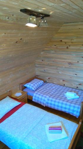 two beds in a room with wooden walls at Eco house in Žabljak