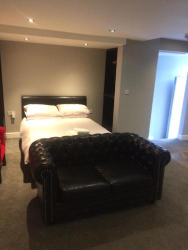 a bedroom with a bed and a black leather couch at Stafford apartments in Stafford