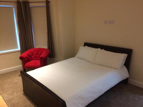 a bedroom with a bed and a red chair at Stafford apartments in Stafford