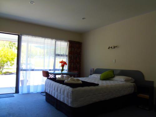 a bedroom with a bed and a large window at Kapiti Lindale Motel and Conference Centre in Paraparaumu