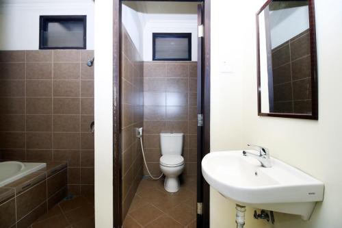 a bathroom with a toilet and a sink and a mirror at Safina Inn Syariah Sekupang Batam in Sekupang