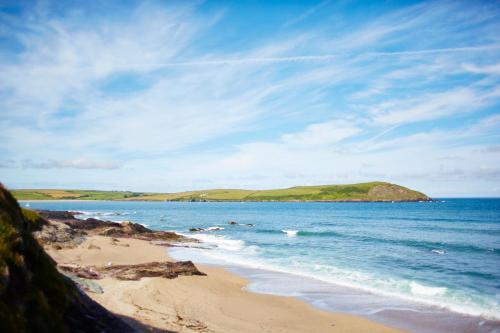 a beach with a small island in the water at St Moritz Hotel and Cowshed Spa in Polzeath