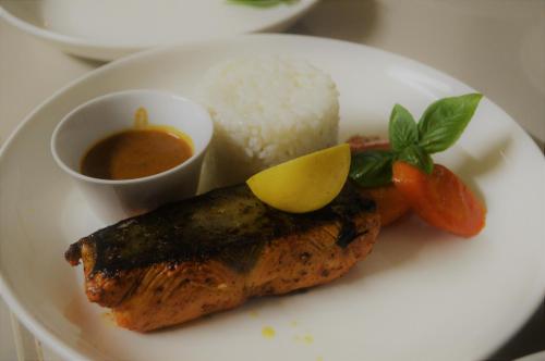 a plate with a fish with rice and a lemon on it at Zanzibar Dream Lodge in Bwejuu