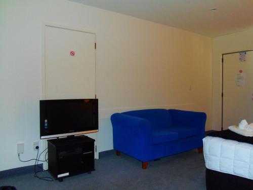 a living room with a blue couch and a tv at Kapiti Lindale Motel and Conference Centre in Paraparaumu