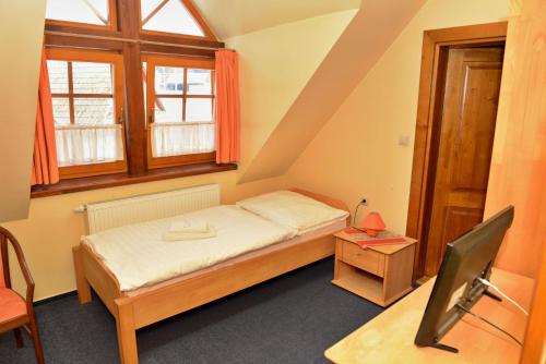 a small bedroom with a bed and a desk and window at Penzión Schweintaal in Bravačov