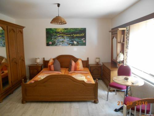 Schlafzimmer mit einem Holzbett und einem Tisch in der Unterkunft Pension "Am Schloß" in Lübben