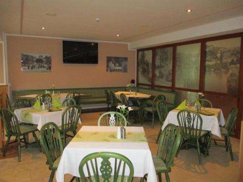 a restaurant with white tables and green chairs and windows at Vitalhotel Weisse Elster in Bad Elster