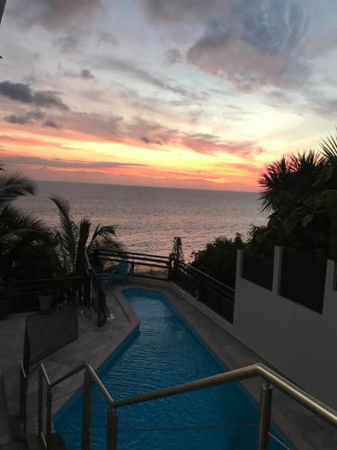 a swimming pool with a view of the ocean at sunset at Nolitha 2 in Manapany-les Bains