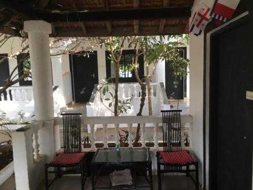two chairs and a table on a porch at God's Gift Morjim in Morjim