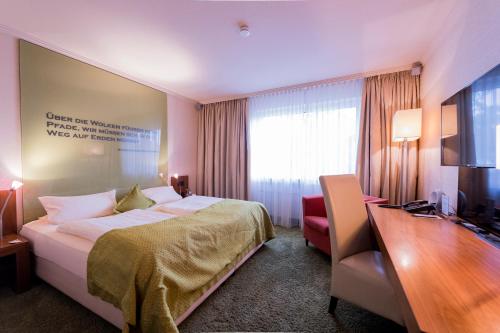 a hotel room with a bed and a desk and a television at Atrium Hotel Mainz in Mainz