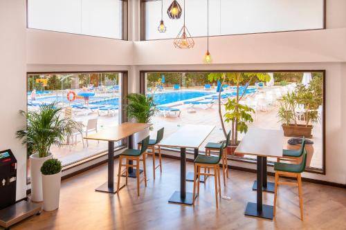 a restaurant with tables and chairs in front of a pool at Hotel Gala Placidia 3'''sup in Benidorm