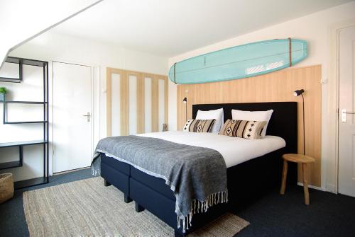 a bedroom with a large bed with a blue headboard at Hotel Zand in Zandvoort